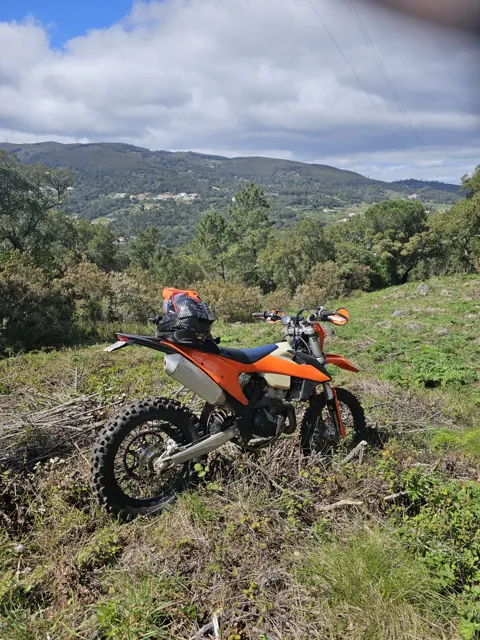 Una KTM arancione su un pendio, con le montagne sullo sfondo.