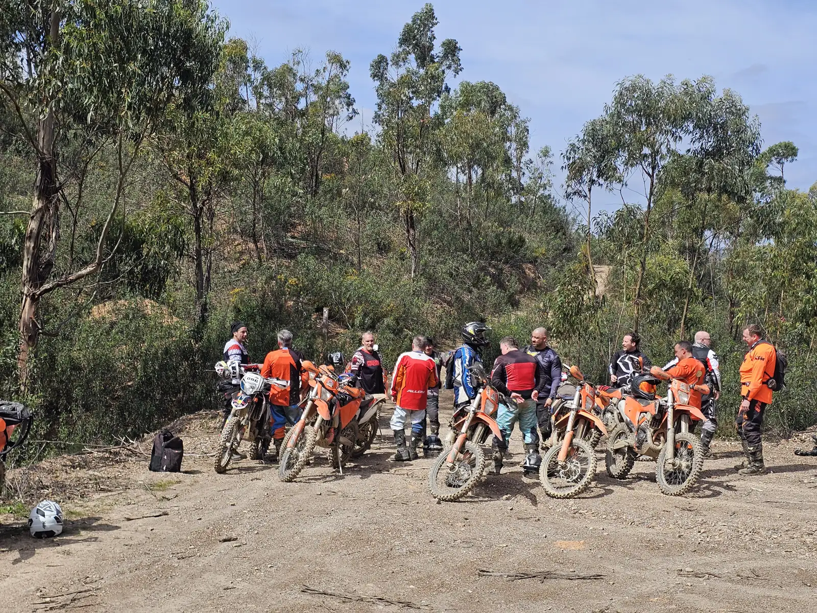 A group of enduro riders taking a break beside a woodland trail