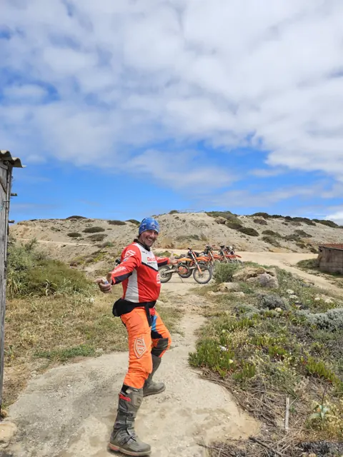 Un pilota di enduro ammira il paesaggio sulla costa di Carrapateira.