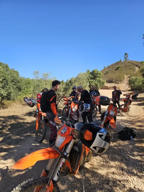 Piloti e moto da enduro durante una sosta all’ombra lungo il sentiero.