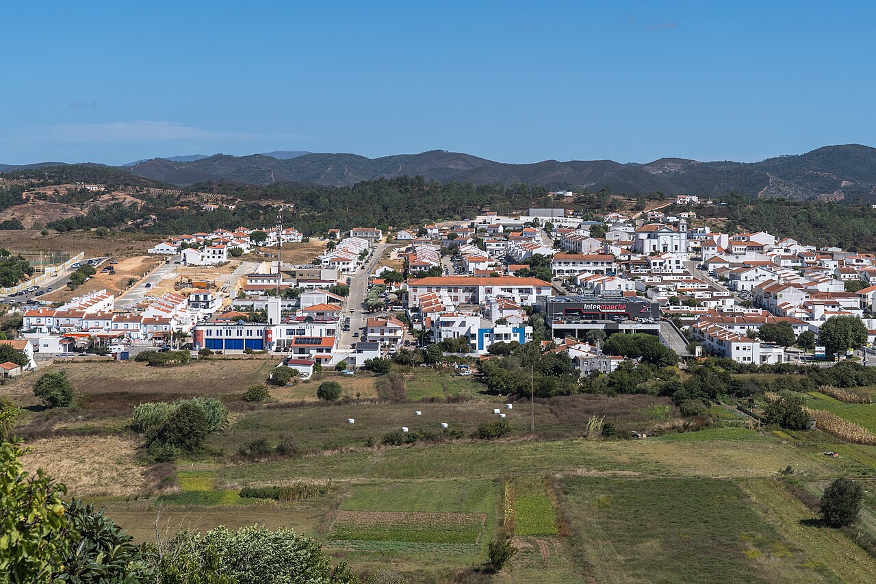 White houses and tiled roofs of Aljezur above the green river valley.
