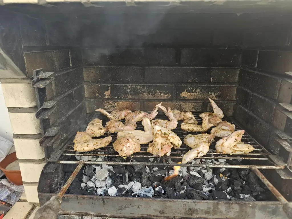 Chicken cooking over charcoal at the Let’s Ride Portugal base
