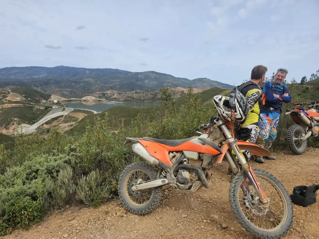 Two enduro riders and KTM bikes overlooking the hills near Silves