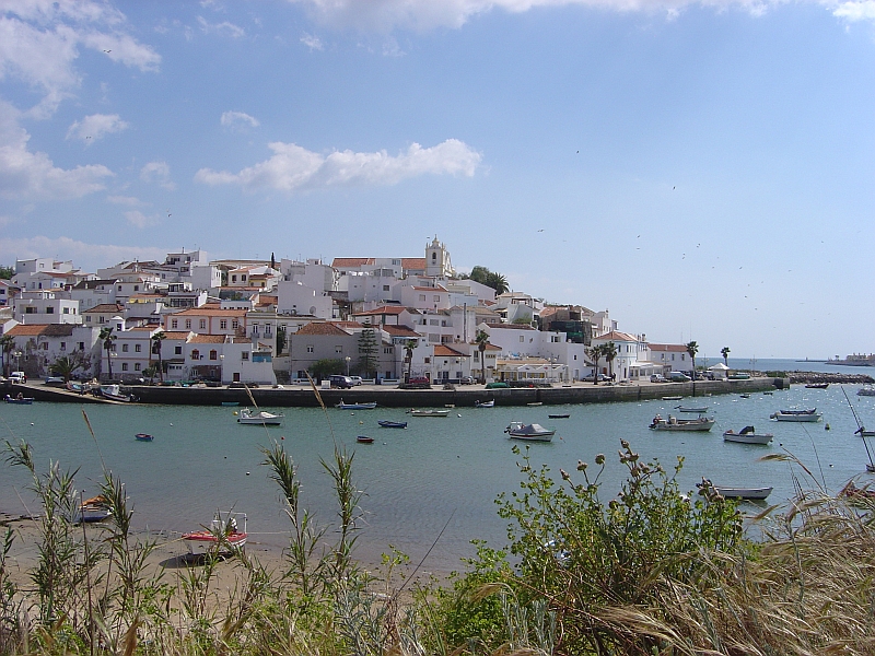 Ferragudo waterfront, fishing boats and white houses rising to the church.