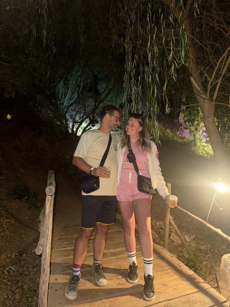 Two guests on a wooden bridge at Friday Happiness in Tojeiro at night.