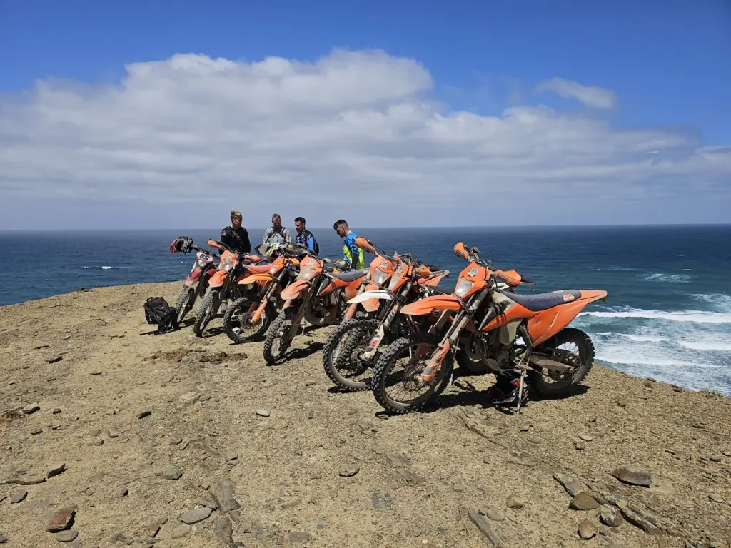 KTM enduro bikes and riders overlooking the Atlantic coast near Carrapateira