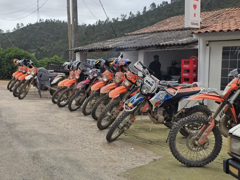 Muddy KTM enduro motorcycles lined up outside Snack-Bar Terinho in the Silves hills.