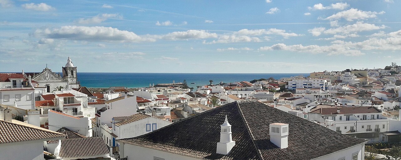 Rooftops and church towers in the historic centre of Lagos, with the sea beyond.